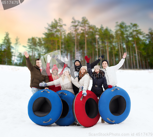 Image of happy friends with snow tubes outdoors in winter