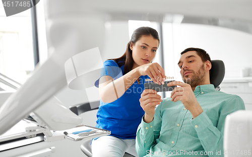 Image of dentist choosing tooth color for patient at clinic