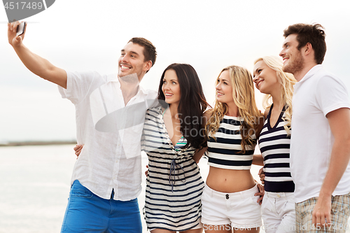 Image of happy friends taking selfie on summer beach