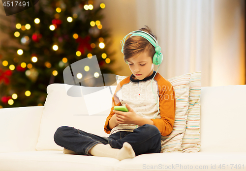 Image of boy with smartphone and headphones on christmas