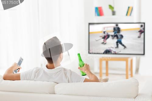 Image of man watching ice hockey on tv and drinking beer