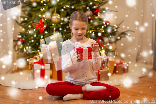Image of smiling girl with christmas gift at home
