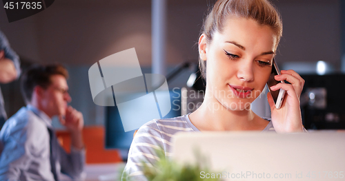 Image of woman using mobile phone in dark office