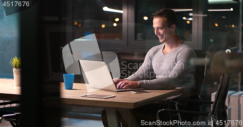 Image of man working on laptop in dark office