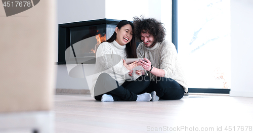 Image of Young Couple using digital tablet on the floor