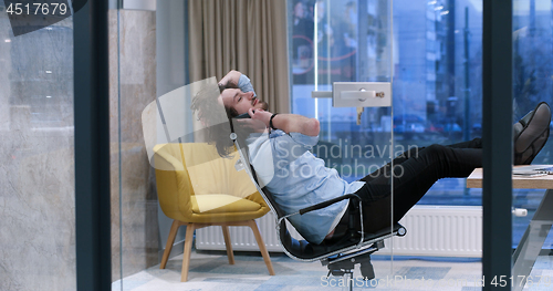 Image of businessman sitting with legs on desk