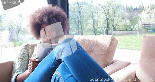 Image of african american woman at home using digital tablet