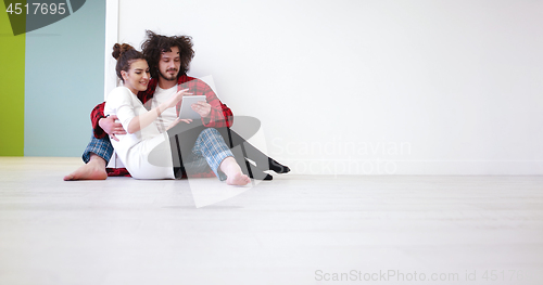 Image of Young Couple using digital tablet on the floor