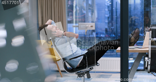 Image of businessman sitting with legs on desk