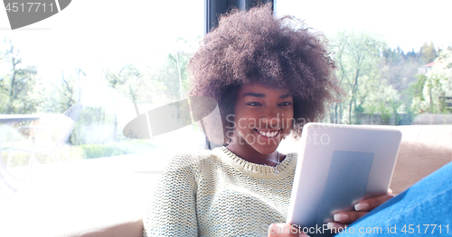 Image of african american woman at home using digital tablet