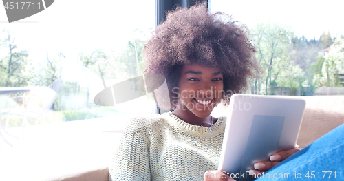 Image of african american woman at home using digital tablet