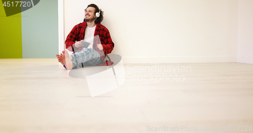 Image of young man listenig music on tablet at home