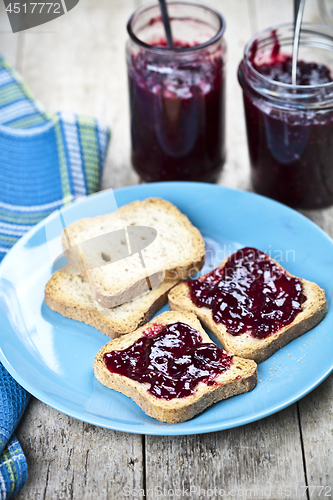 Image of Fresh cereal bread slices on blue ceramic plate, homemade cherry