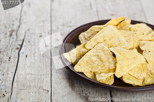 Image of Nachos chips on brown ceramic plate. 