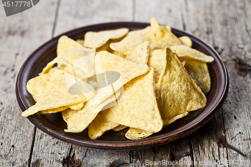 Image of Nachos chips on brown ceramic plate. 