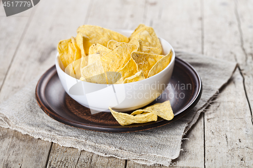 Image of Mexican nachos chips in white bowl on brown ceramic plate on lin