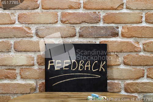 Image of Chalk board with the word FEEDBACK drown by hand and chalks on w