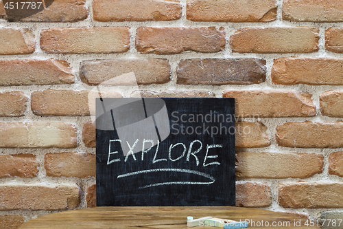Image of Chalk board with the word EXPLORE drown by hand and chalks on wo