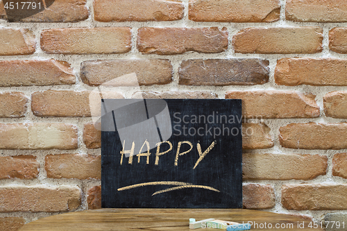 Image of Chalk board with the word HAPPY drown by hand and chalks on wood