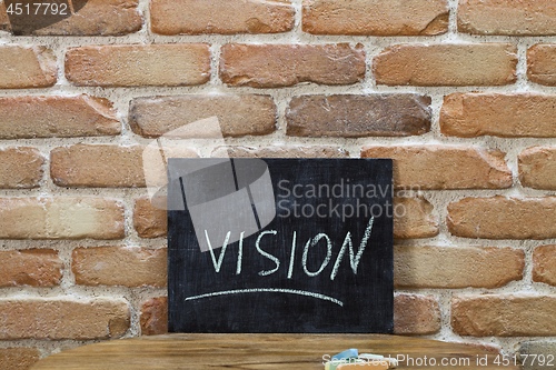 Image of Chalk board with the word VISION drown by hand and chalks on woo