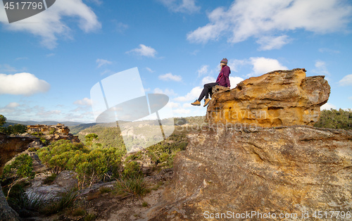 Image of A bushwalker sits high atop a landscape of pagodas, valleys, gullies and canyons