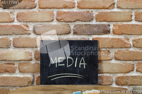 Image of Chalk board with the word MEDIA drown by hand and chalks on wood