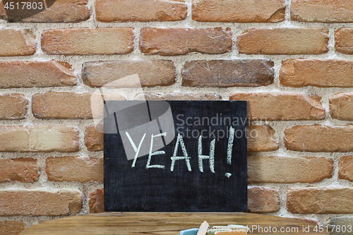 Image of Chalk board with the word YEAH! drown by hand and chalks on wood