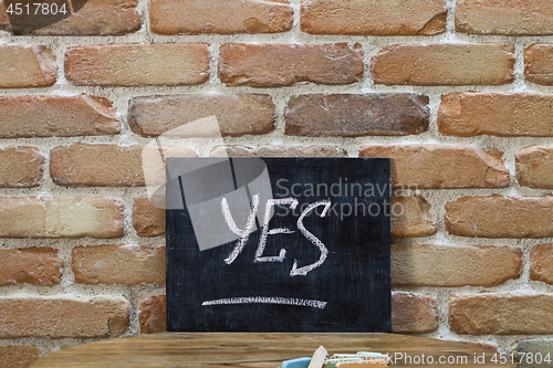 Image of Chalk board with the word YES drown by hand and chalks on wooden