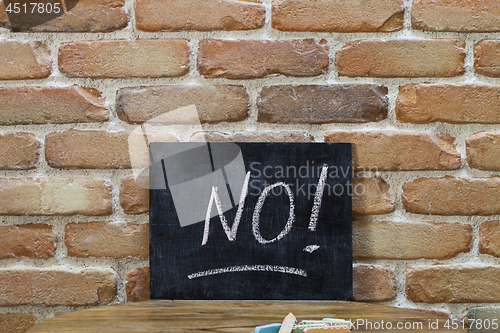 Image of Chalk board with the word NO! drown by hand and chalks on wooden