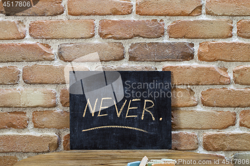 Image of Chalk board with the word NEVER drown by hand and chalks on wood