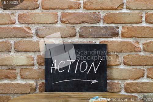 Image of Chalk board with the word ACTION drown by hand and chalks on woo