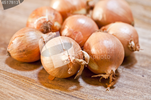 Image of Fresh organic onions heap closeup on rustic wooden table.