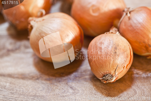 Image of Fresh organic onions heap closeup on rustic wooden background. 