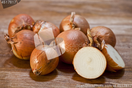 Image of Organic fresh onions heap closeup on rustic wooden table.