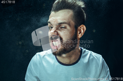 Image of Young handsome man with beard sneezing, studio portrait