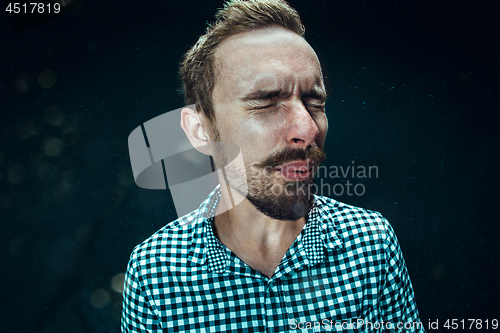 Image of Young handsome man with beard sneezing, studio portrait