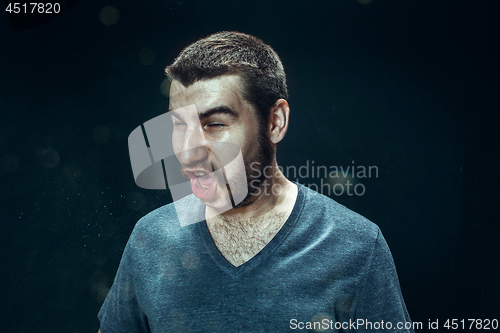 Image of Young handsome man with beard sneezing, studio portrait