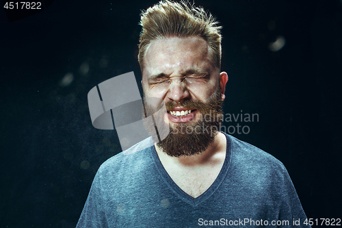 Image of Young handsome man with beard sneezing, studio portrait