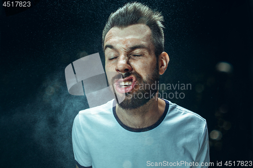 Image of Young handsome man with beard sneezing, studio portrait