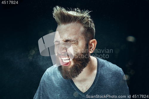 Image of Young handsome man with beard sneezing, studio portrait