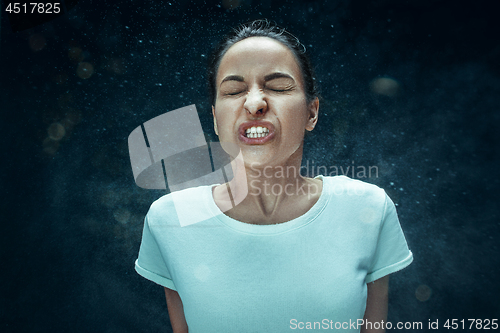 Image of Young woman sneezing, studio portrait