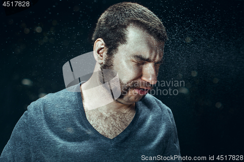 Image of Young handsome man with beard sneezing, studio portrait