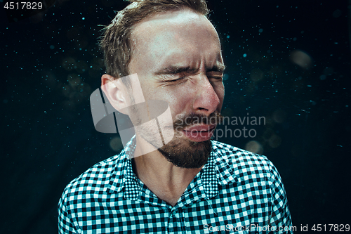 Image of Young handsome man with beard sneezing, studio portrait