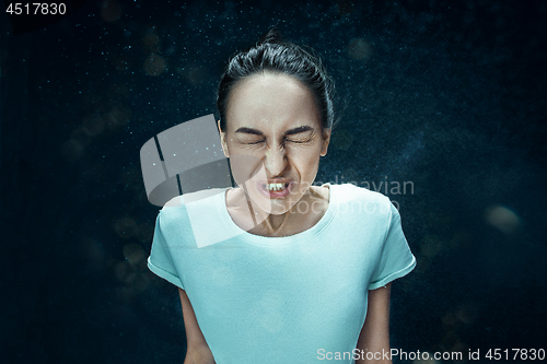 Image of Young woman sneezing, studio portrait