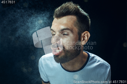 Image of Young handsome man with beard sneezing, studio portrait