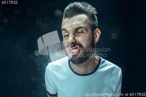 Image of Young handsome man with beard sneezing, studio portrait