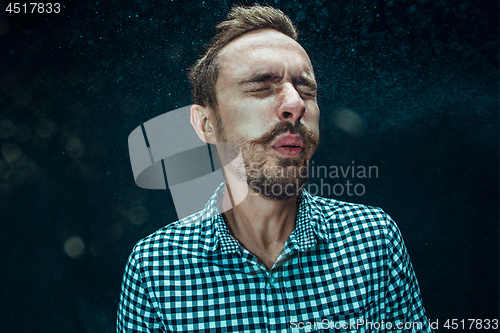 Image of Young handsome man with beard sneezing, studio portrait