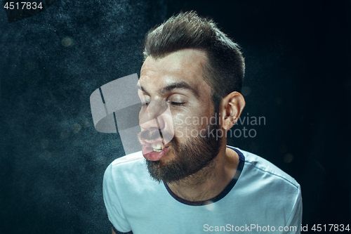 Image of Young handsome man with beard sneezing, studio portrait