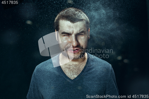 Image of Young handsome man with beard sneezing, studio portrait