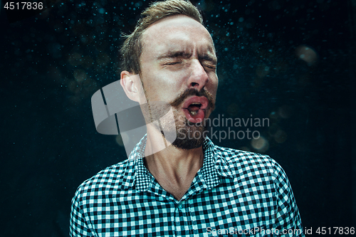 Image of Young handsome man with beard sneezing, studio portrait